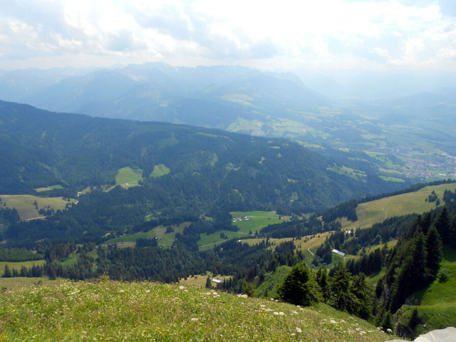 Ausblick vom Grünten hinab ins Tal, das von der Starzlach geschaffen wurde. Am Rande ist Sonthofen zu erahnen